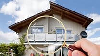 Image of someone with a magnifying glass looking at a house